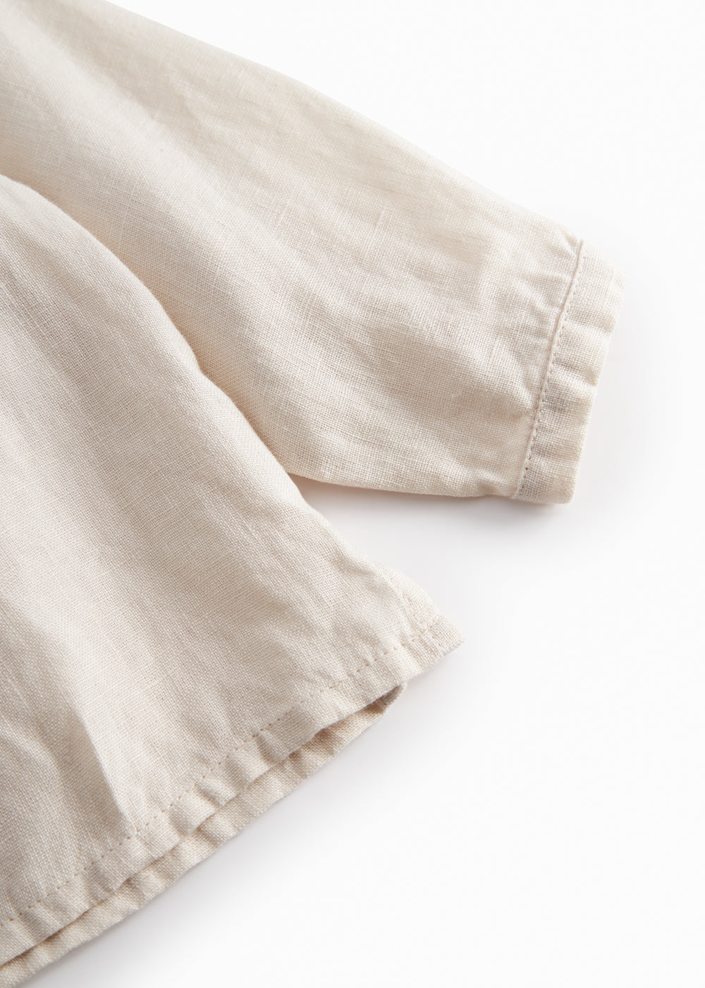 Sleeveless beige top for baby with ruffle details.