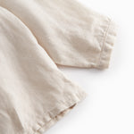 Sleeveless beige top for baby with ruffle details.