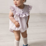 Baby wearing light lavender dress with short sleeves and ruffled details.
