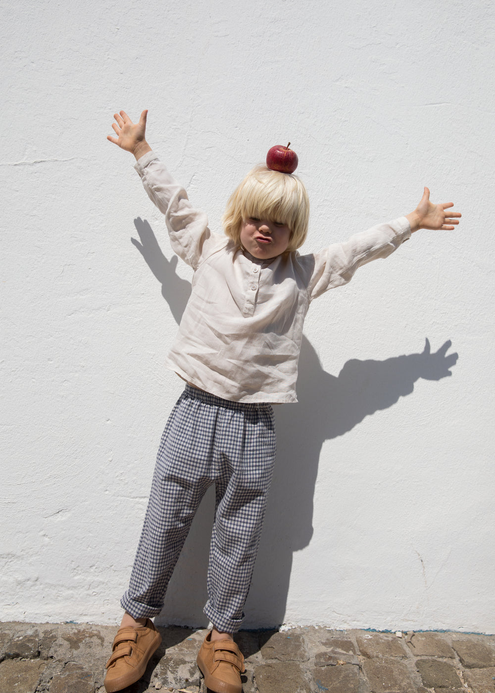 Child wearing a beige shirt and netted pants.