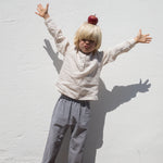 Child wearing a beige shirt and netted pants.