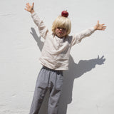 Child wearing a beige shirt and netted pants.