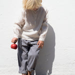 Child wearing a beige shirt and netted pants.