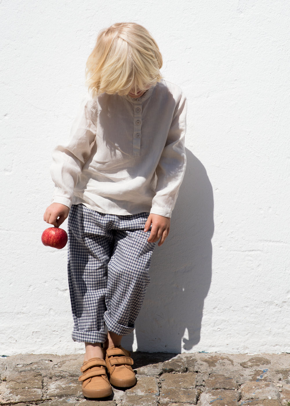Child wearing a light sweater and dirty pants with toys in hand.