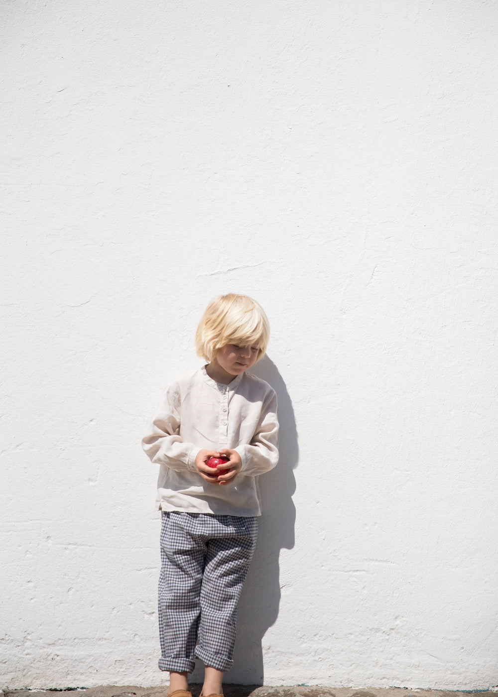 Child wearing a beige shirt and netted pants.