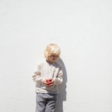 Child wearing a beige shirt and netted pants.