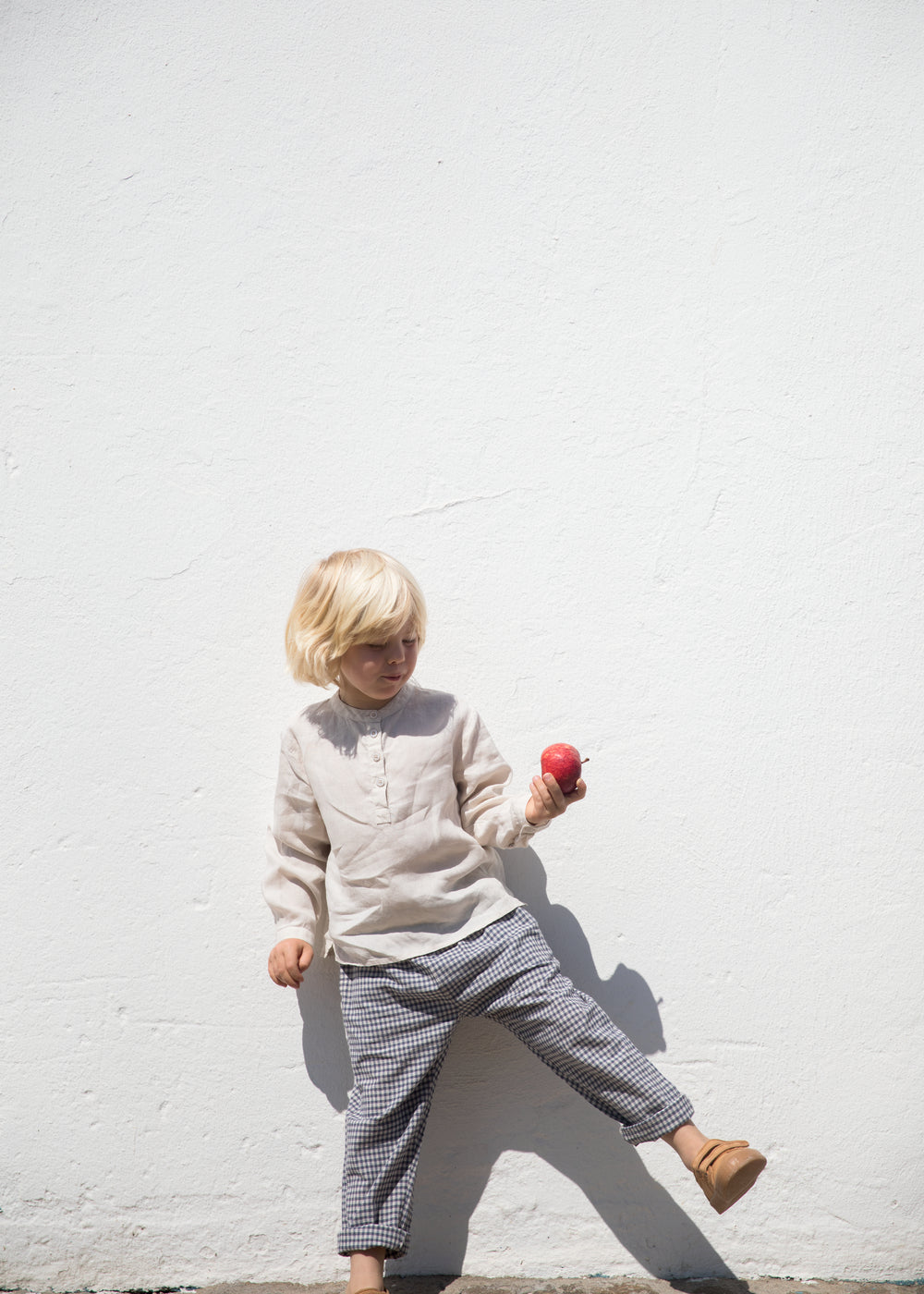 Child wearing a beige shirt and netted pants.