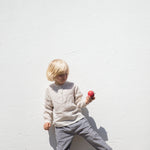 Child wearing a light sweater and dirty pants