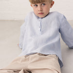 Boy in a light blue shirt and beige pants
