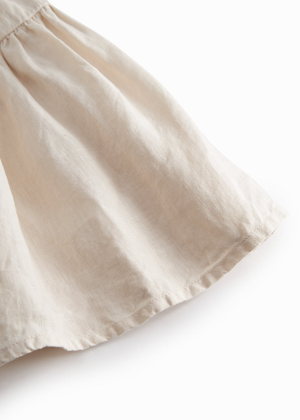 Sleeveless beige dress for children with wide straps and flaps on the shoulder and a smock at the back.