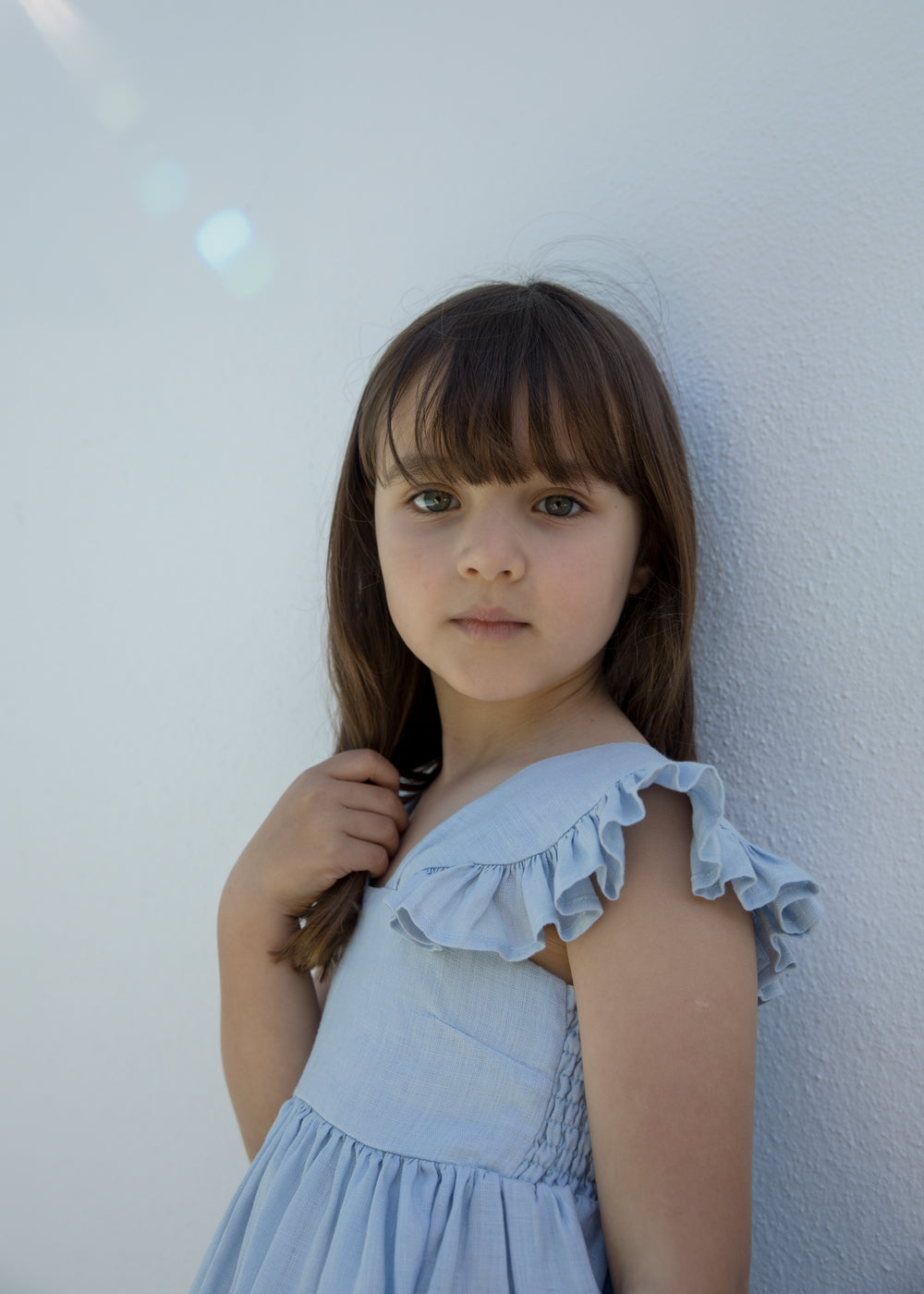 Child wearing a light blue dress with puffed sleeves.