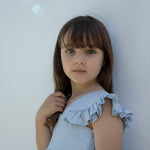 Child wearing a light blue dress with puffed sleeves.
