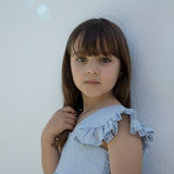 Child wearing a light blue dress with puffed sleeves.