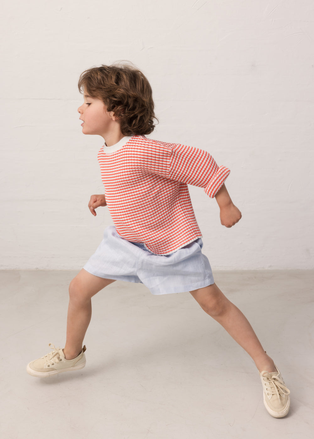 Child wearing a striped shirt and light shorts.