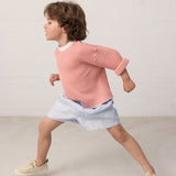 Child wearing a striped shirt and light shorts.