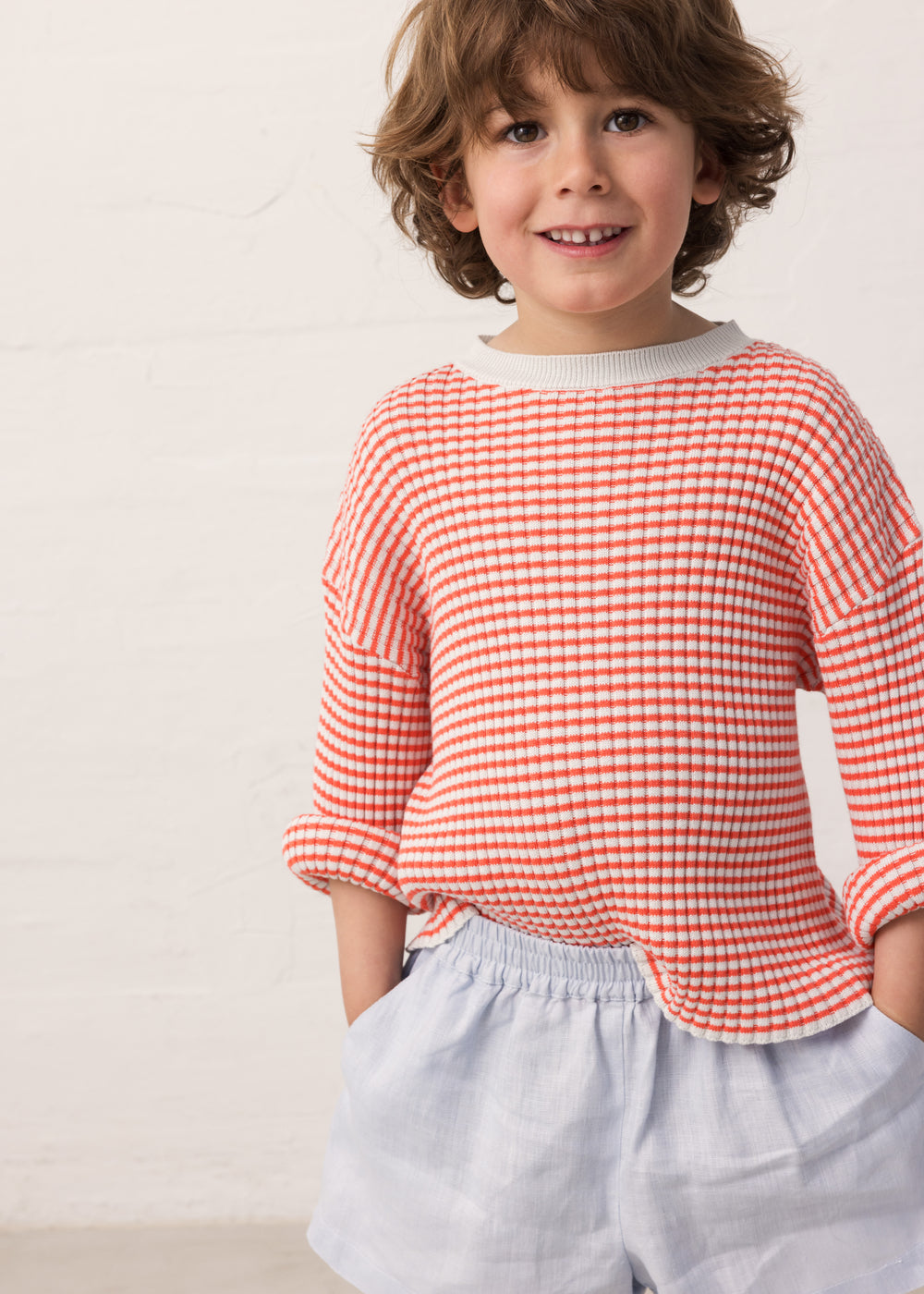 Child wearing a striped shirt and light shorts.