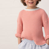 Child wearing a striped shirt and light shorts.