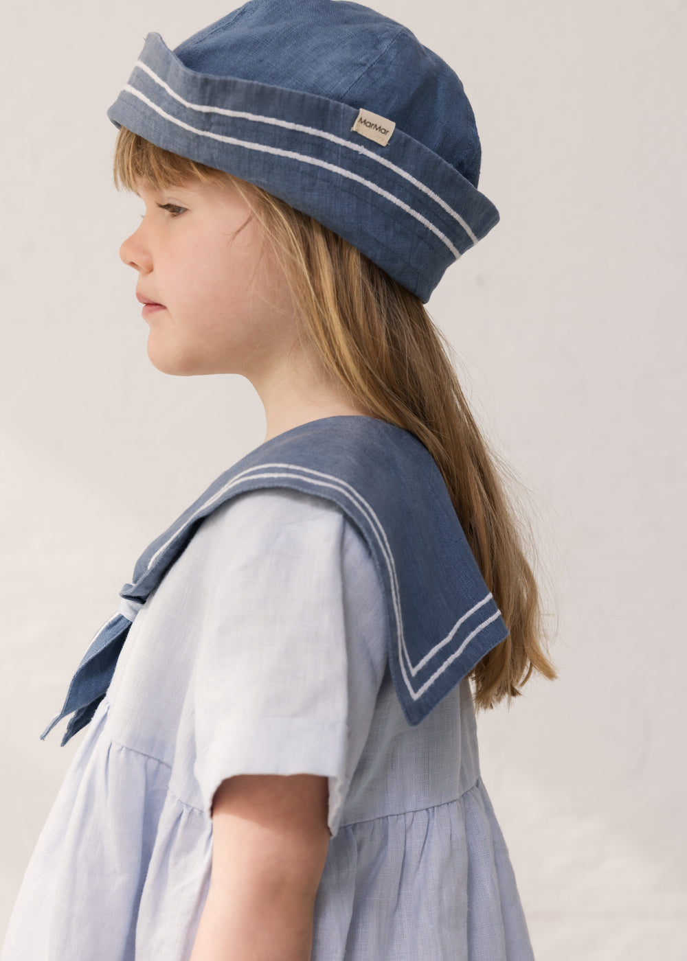 Child wearing a blue matroshka hat and a sailor-inspired dress