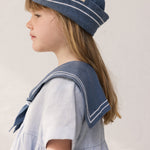 Child wearing a blue matroshka hat and a sailor-inspired dress