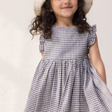 Child wearing a net dress with ruffles and a summer hat.