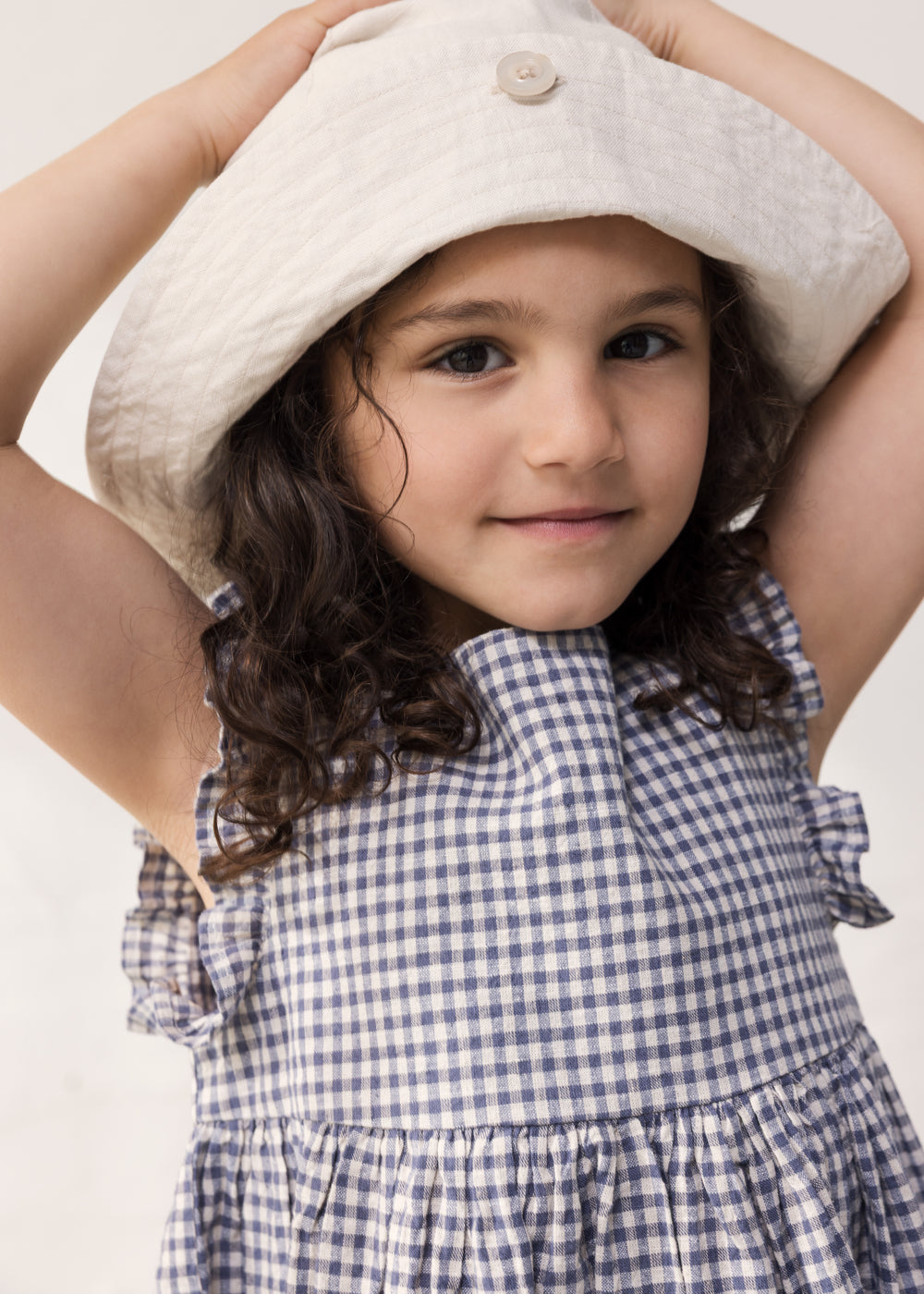 Child wearing a net dress with ruffles and a summer hat.