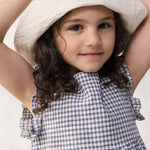 Child wearing a net dress with ruffles and a summer hat.