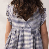 Child wearing a ternet dress with flared sleeves and a hat.