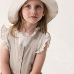 Child wearing a light dress with puffed sleeves and a hat in matching color.