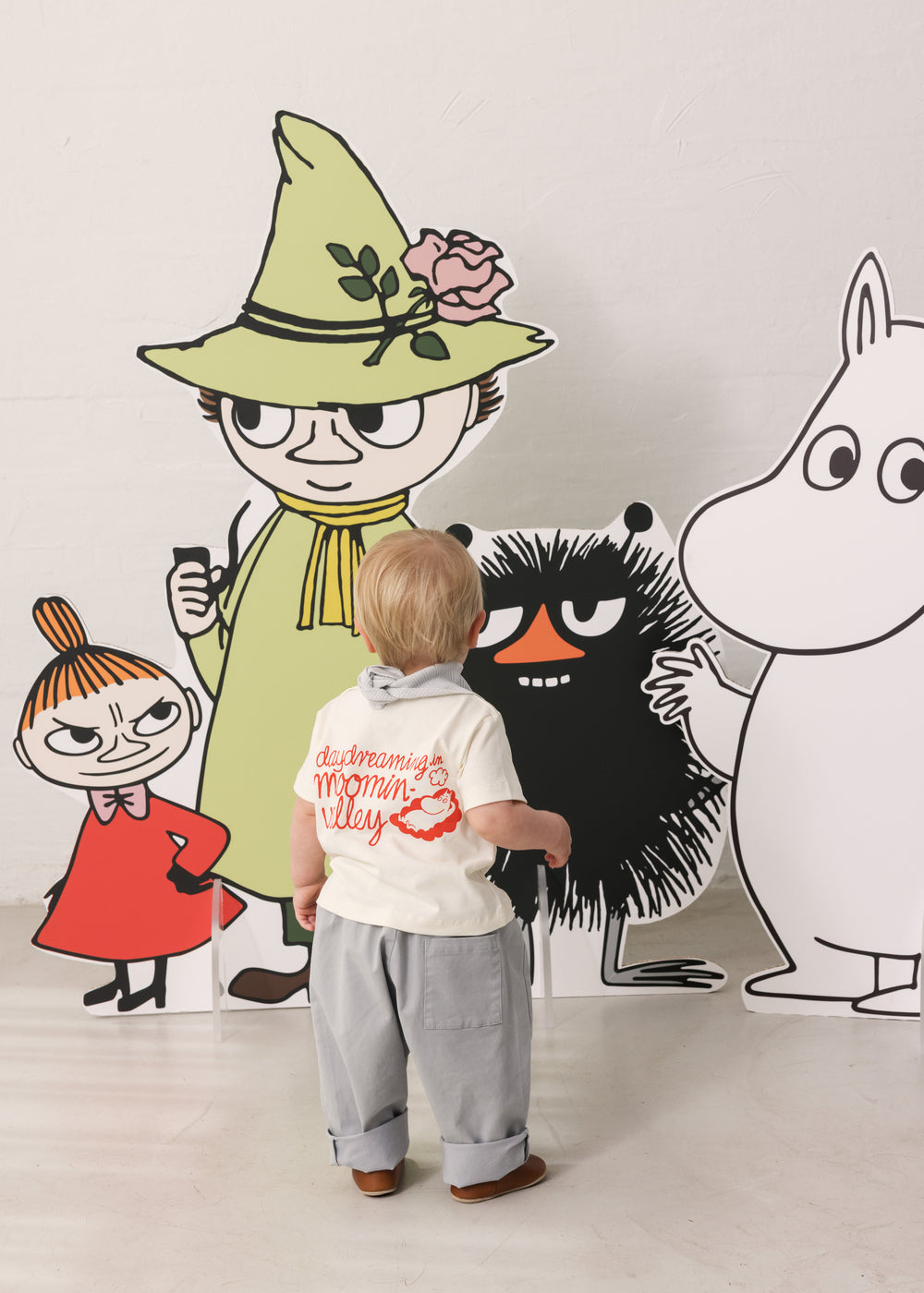 Children are dressed in light T-shirts and pants in front of Mumin figures.