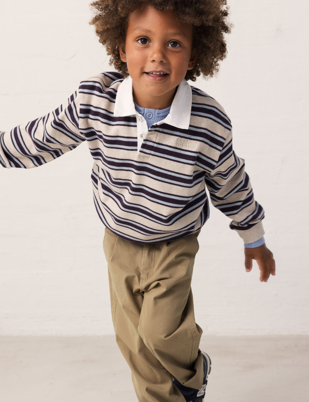 Children in motion wearing a striped shirt and green pants.