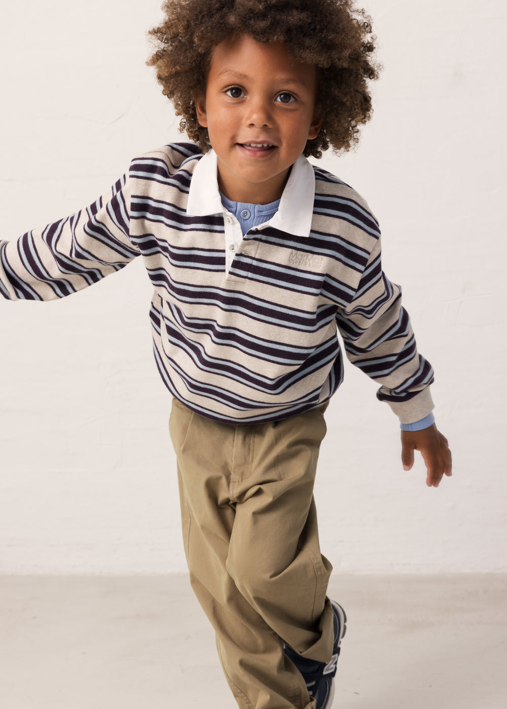 Children in motion wearing a striped shirt and green pants.