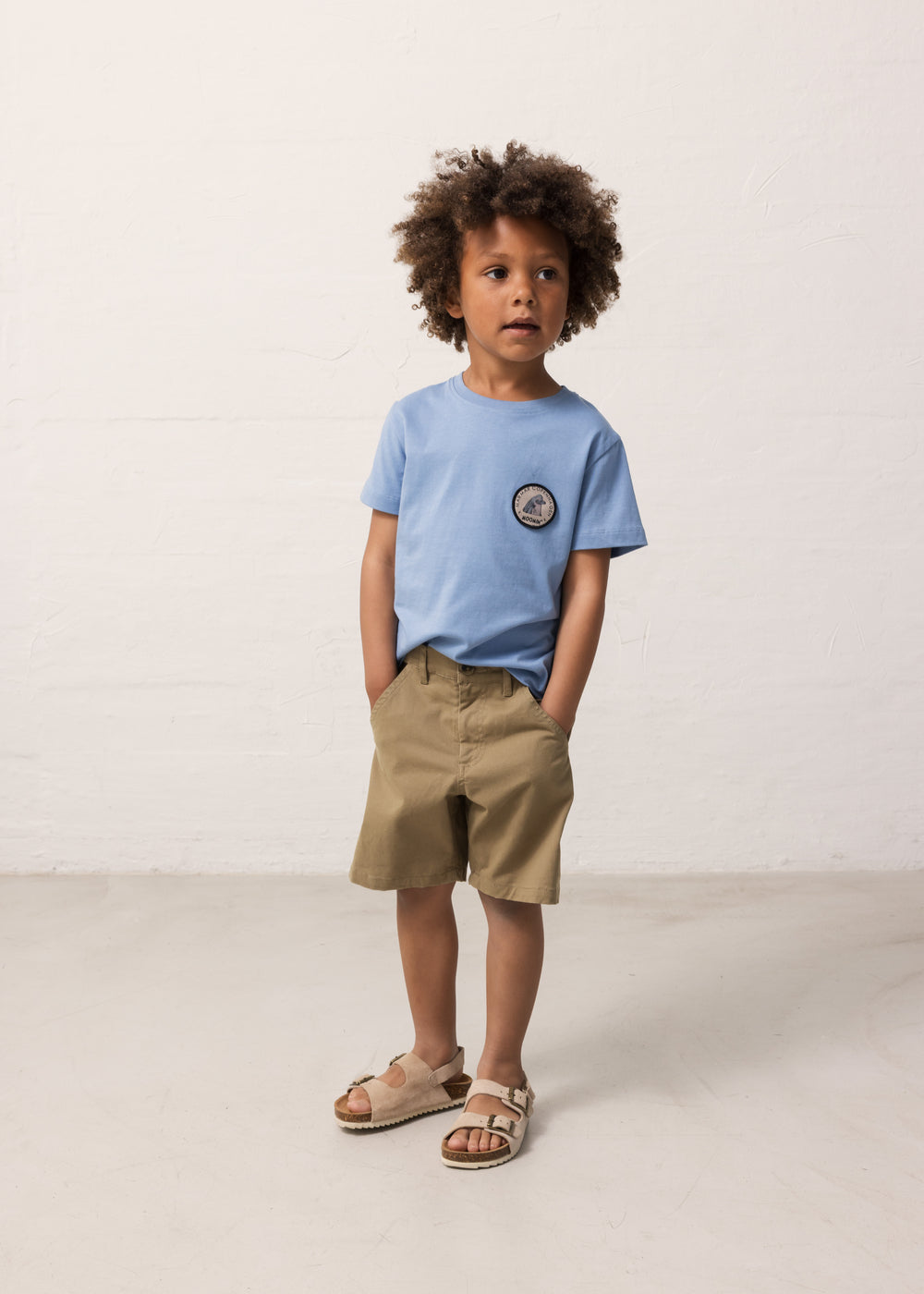 Child wearing a light blue T-shirt and khaki shorts
