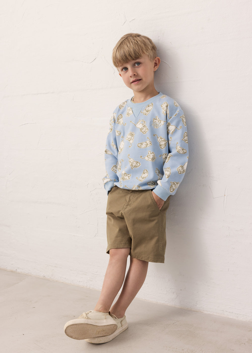 Child wearing a blue Moomin sweatshirt and green shorts