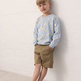 Child wearing a blue Moomin sweatshirt and green shorts