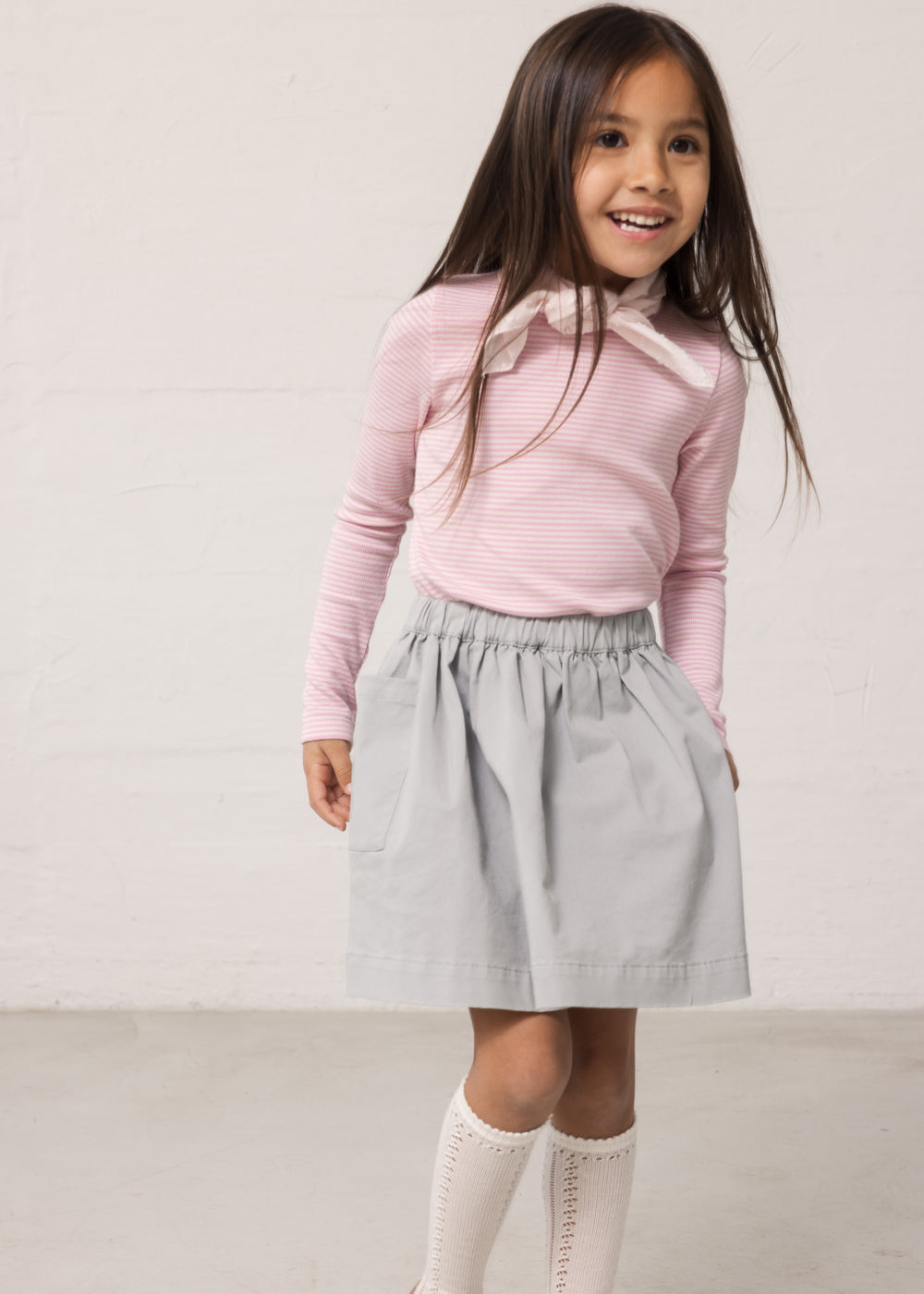 Wearing a long-sleeved t-shirt with bright red stripes and a blue canvas bottom.