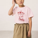 Wearing a green chino bottom and a bright red t-shirt.