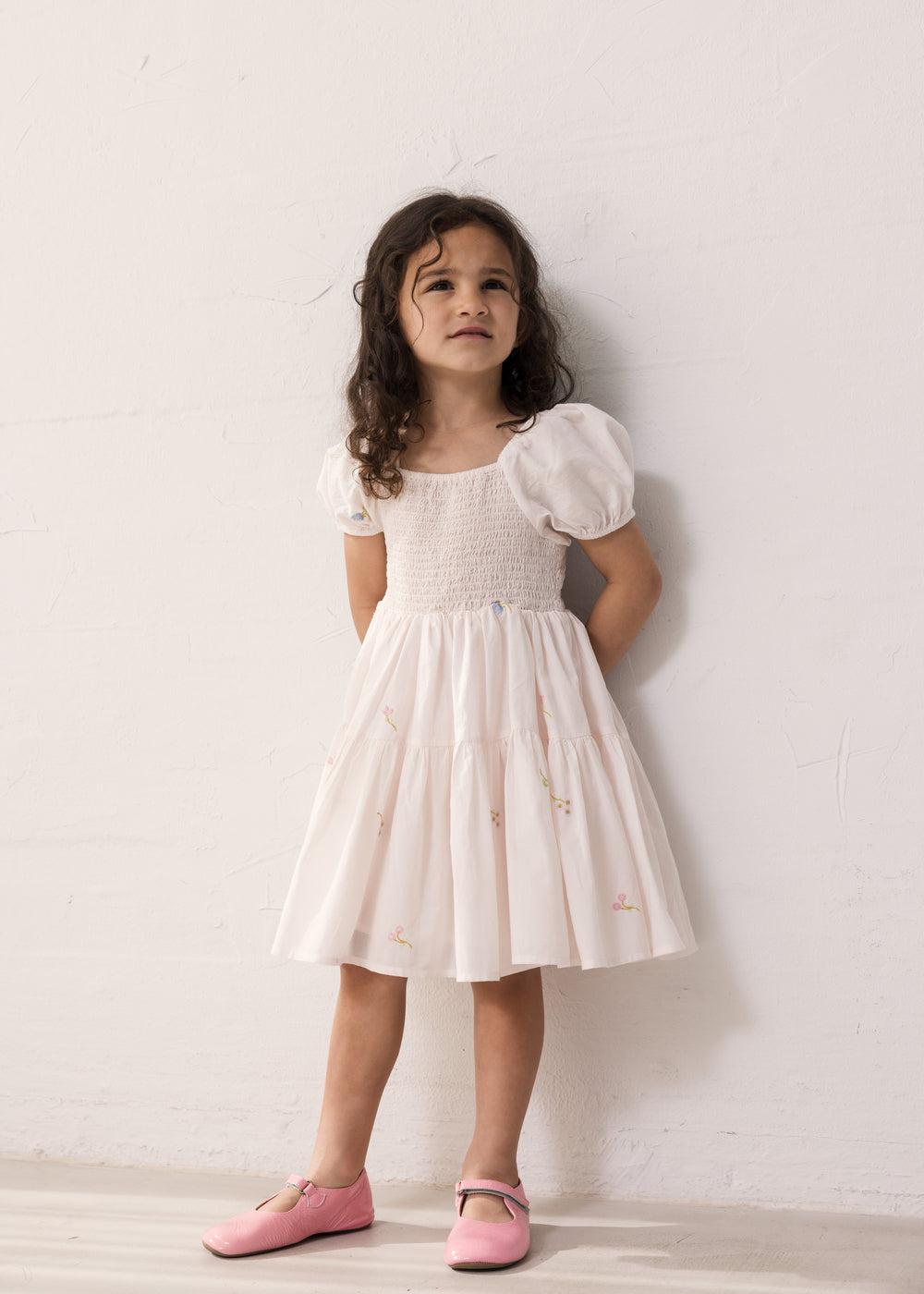 Pige iført lyserød kortærmet lagdelt kjole til børn med et fint blomster broderi, pufærmer og smockeffekt

Girl wearing a bright red short-sleeved layered dress with children, fine flower embroidery, puff sleeves, and smock effect.