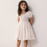 Pige iført lyserød kortærmet lagdelt kjole til børn med et fint blomster broderi, pufærmer og smockeffekt

Girl wearing a bright red short-sleeved layered dress with children, fine flower embroidery, puff sleeves, and smock effect.