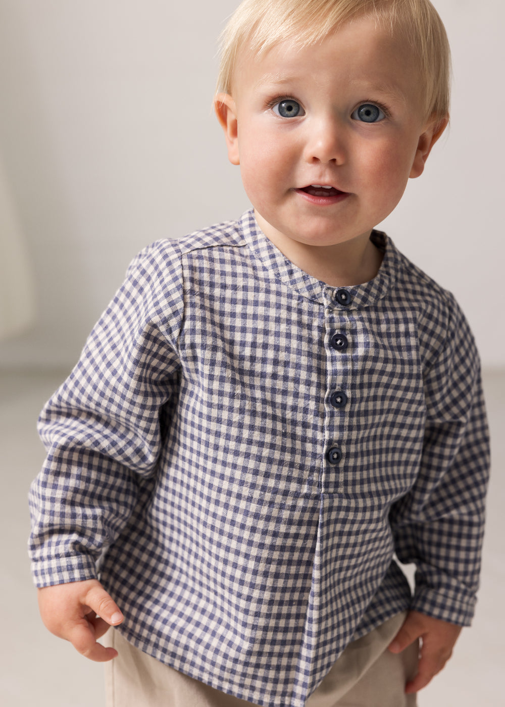 Baby wearing a long-sleeved turtleneck shirt with a collar and front closure.