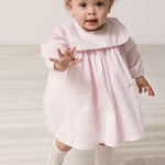 Baby wearing a bright red dress with a collar and long sleeves.