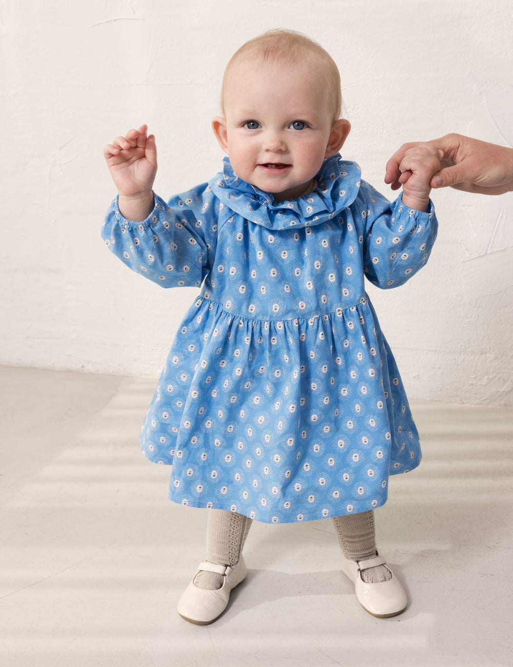 Baby wearing a blue dress with small flowers.