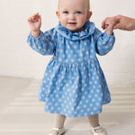 Baby wearing a blue dress with small flowers.