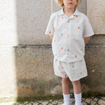 Children wearing a bright set with short sleeves and fruit embroidery, matching a beanie hat.