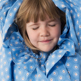 Child wearing a blue dress with a floral print and lace detail.
