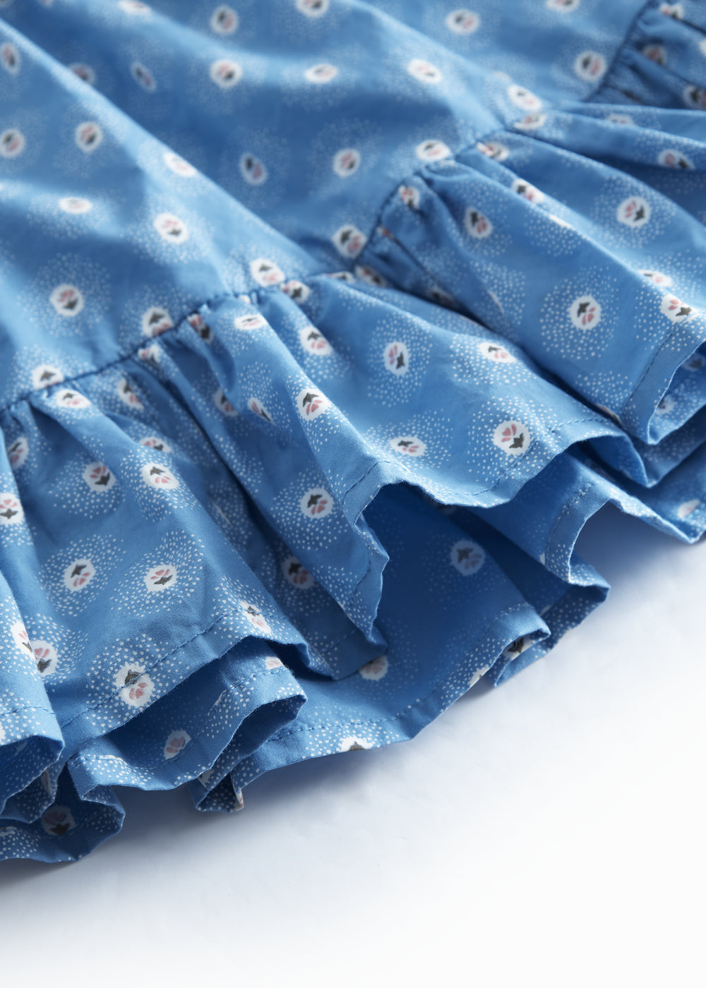 Blue children's pants with small flowers and fringed edges.