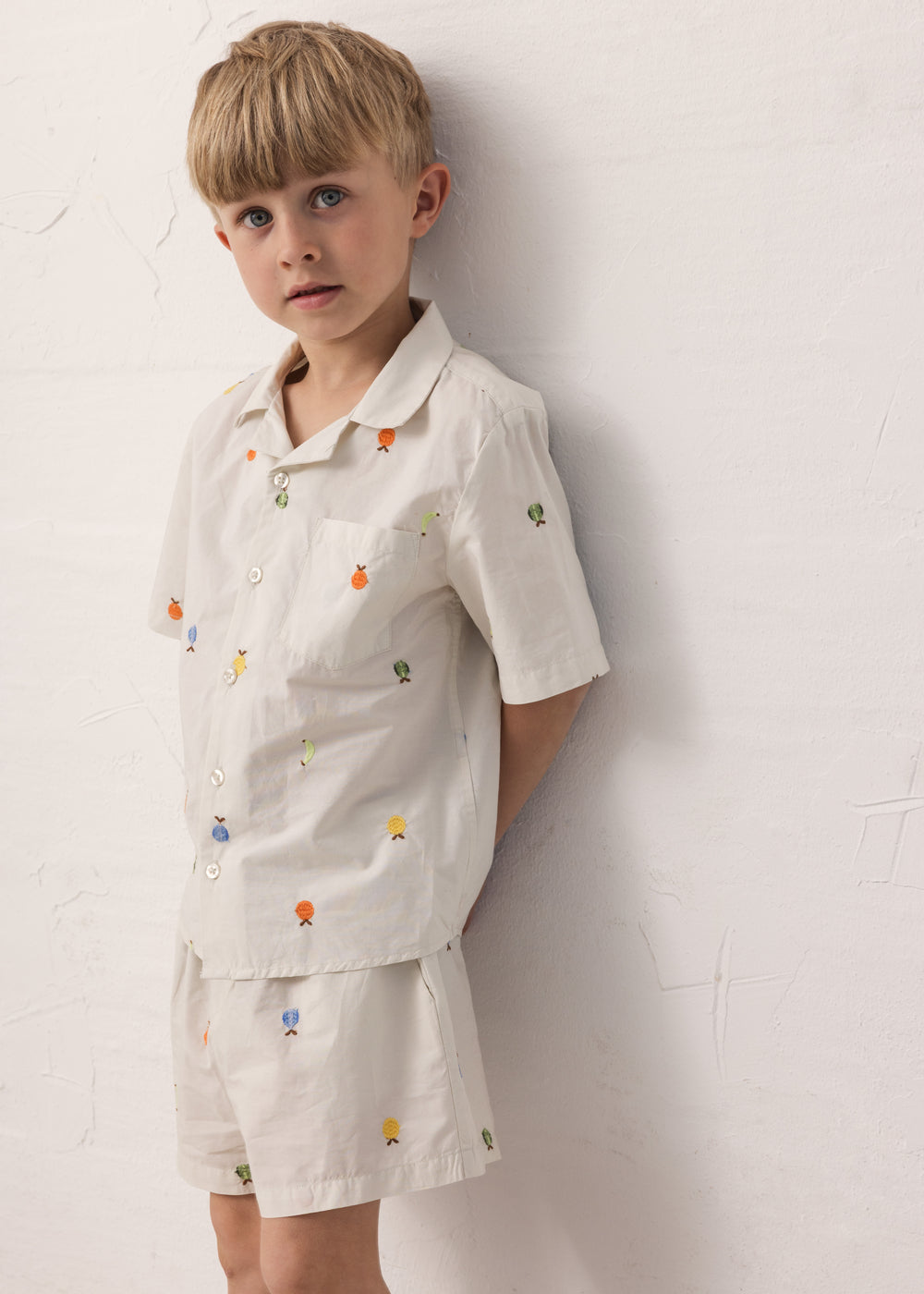 Children wearing a shirt set with fruit embroidery and matching shorts.