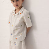 Children wearing a shirt set with fruit embroidery and matching shorts.