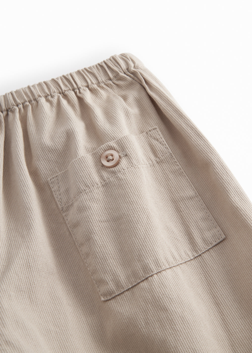 Gray children's jacket with a round neck, two buttons in front, and fine pleated details.