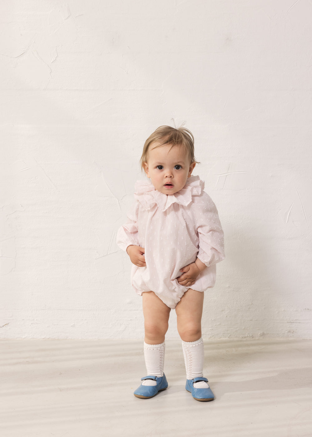 Baby wearing a bright red dress with long sleeves and a peter pan collar.