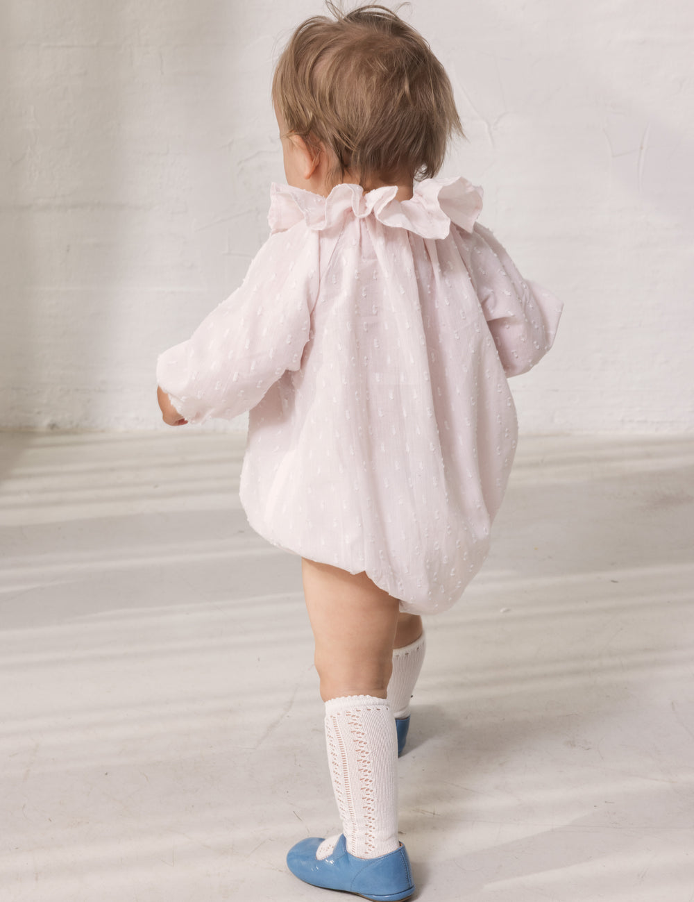 Baby wearing a bright red dress with long sleeves and a peter pan collar.
